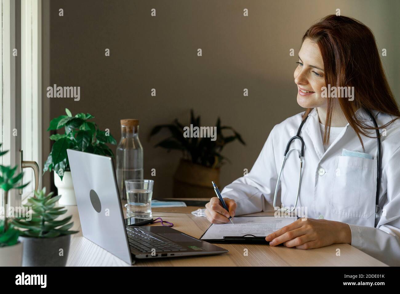 Junge Ärztin, die medizinischen Bericht während der Online-Beratung von Heimbüro Stockfoto