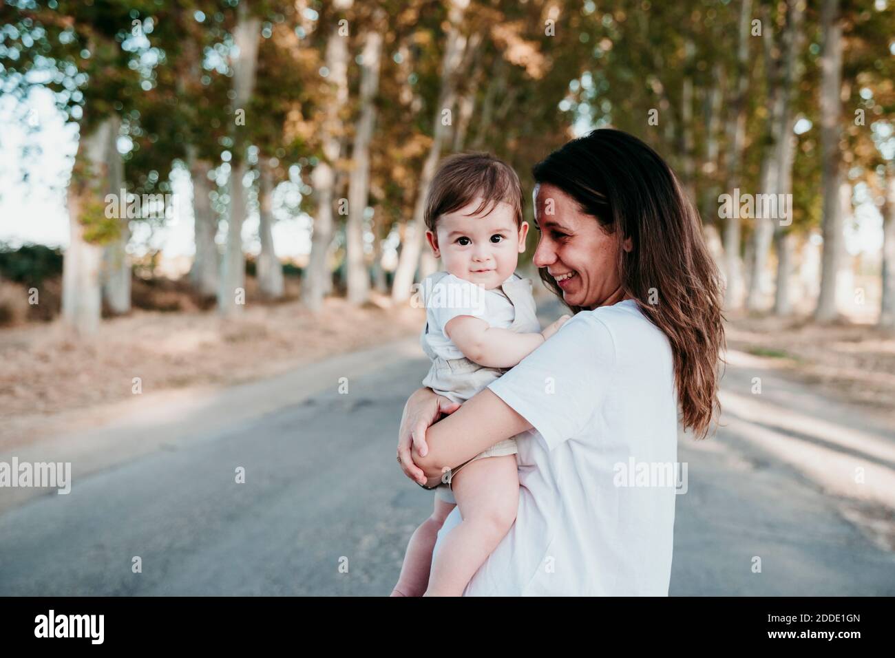 Lächelnde Mutter trägt Baby Junge, während im Freien stehen Stockfoto