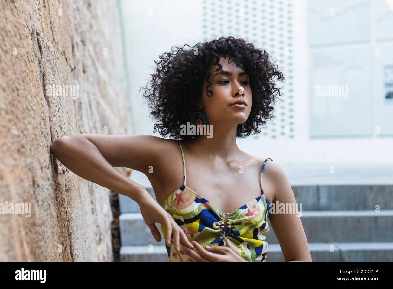 Junge Frau, die an einer Steinwand auf einer Treppe steht Stockfoto