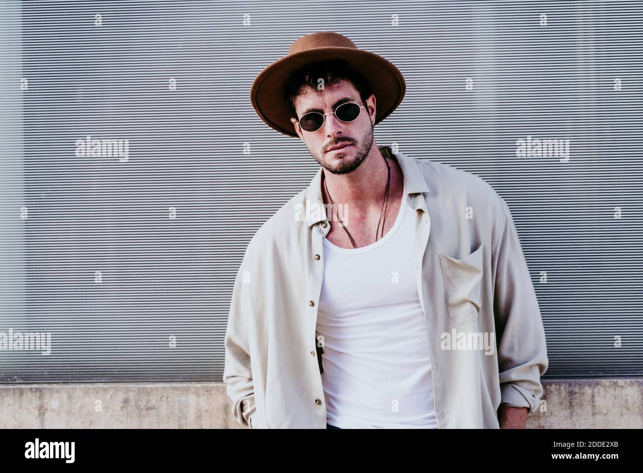 Betrachtend Mann im Hut, der gegen Wand steht Stockfoto