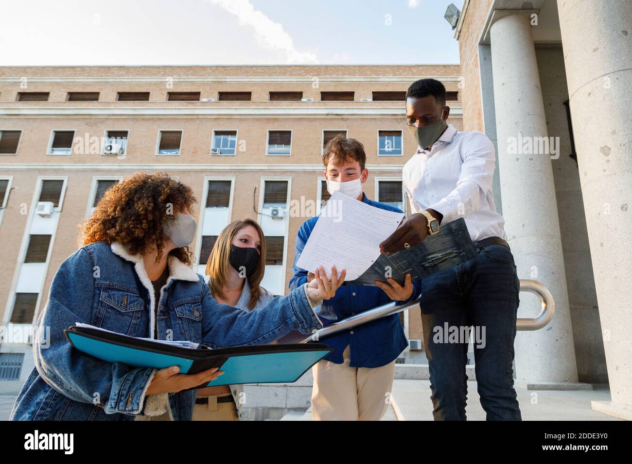 Männliche und weibliche Schüler tragen Sicherheitsmaske während der Diskussion in Universitätsgelände Stockfoto