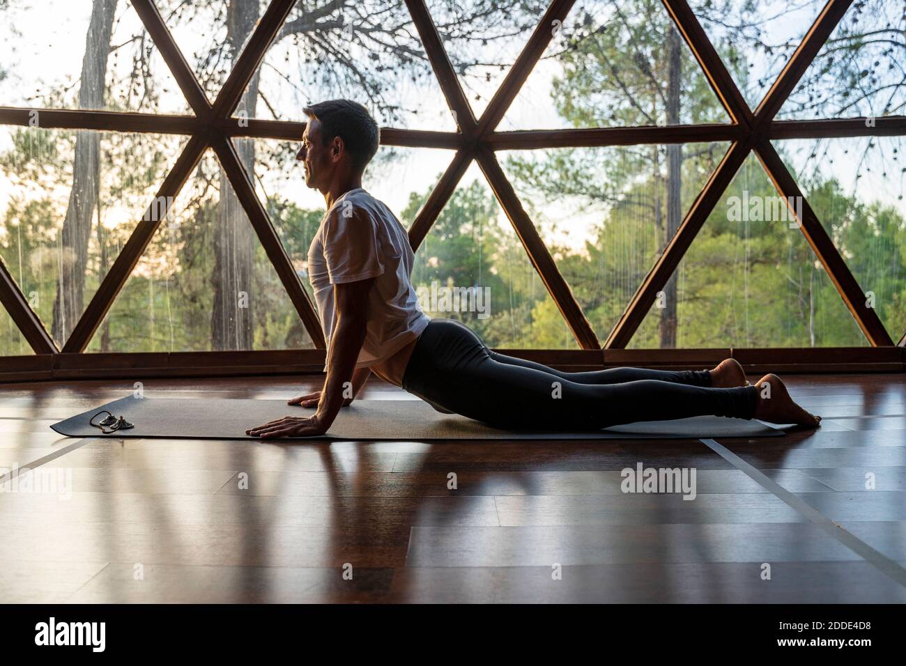 Reifer Mann praktiziert Yoga auf Matte im Wellness-Center Stockfoto