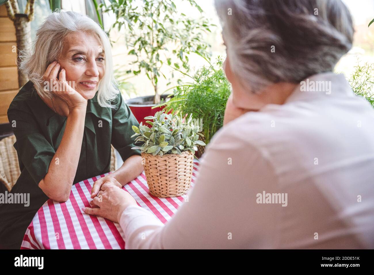 Reife Frau mit Kopf in den Händen sitzen von Freund an Restaurant Stockfoto