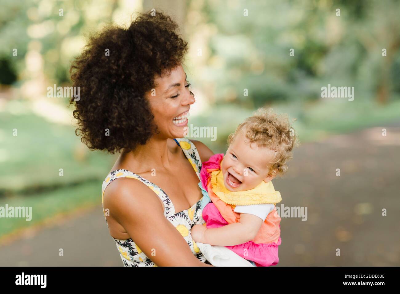 Fröhliche Mutter hält Baby, während sie im Park steht Stockfoto