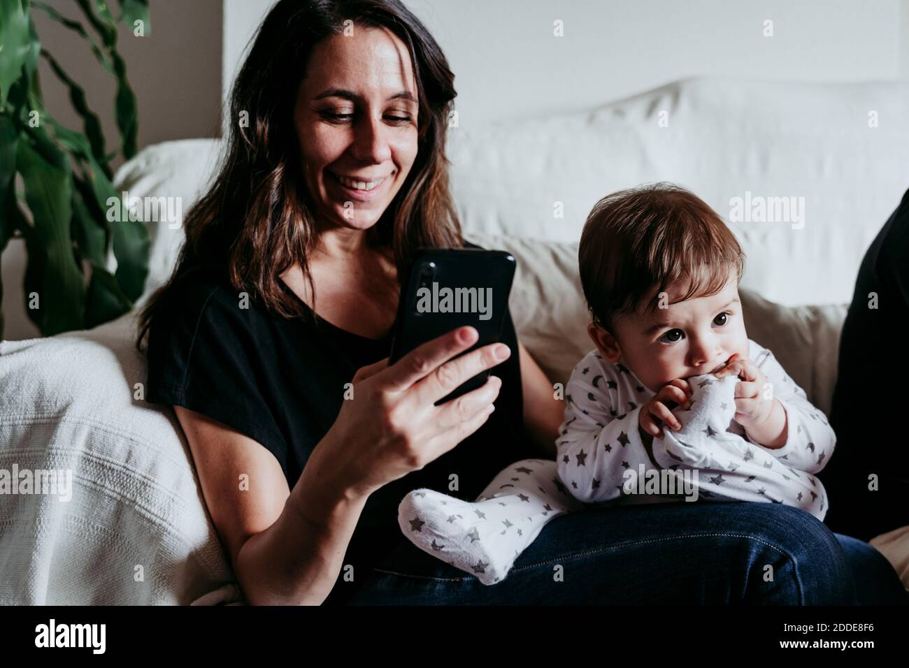 Mutter SMS auf Smartphone mit Sohn sitzen auf Sofa zu Hause Stockfoto