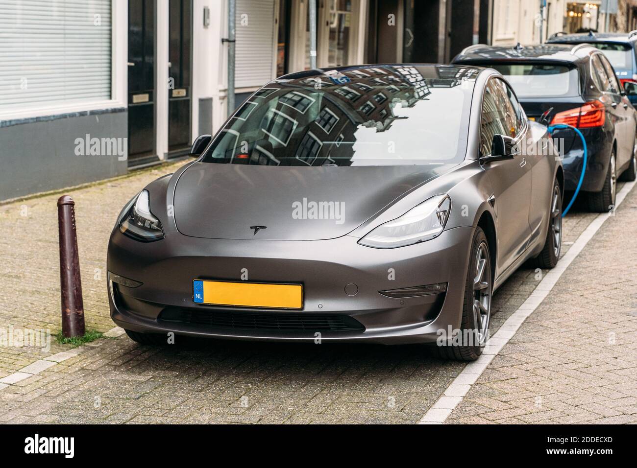 Amsterdam, Niederlande - März 2020 : Tesla modernes Elektroauto wird an der Ladestation auf der Straße in der europäischen Stadt geparkt.Tesla - amerikanische Firma, Hersteller von Elektrofahrzeugen und nicht nur. Stockfoto