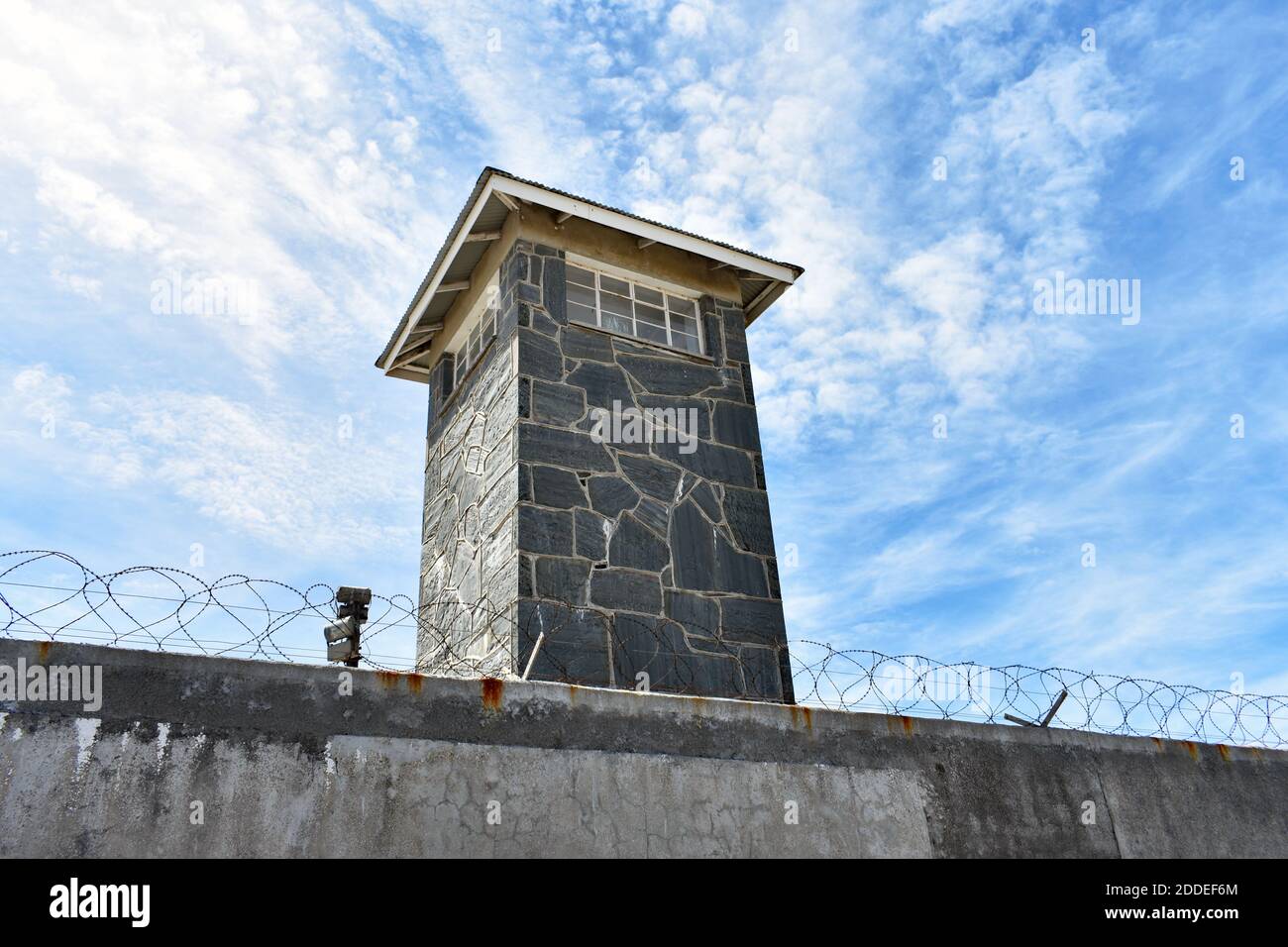 Ein großer Wachturm hinter einer mit Stacheldraht überdeckten Wand im Hochsicherheitsgefängnis auf Robben Island, Kapstadt, Südafrika Stockfoto