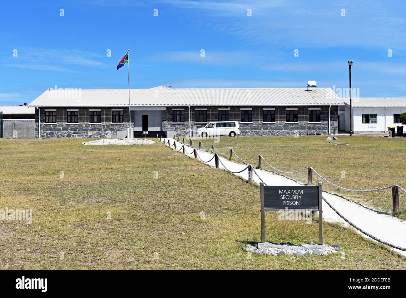 Ein Pfad führt über Gras zum Hochsicherheitsgefängnis auf Robben Island, Kapstadt, Südafrika, Stockfoto