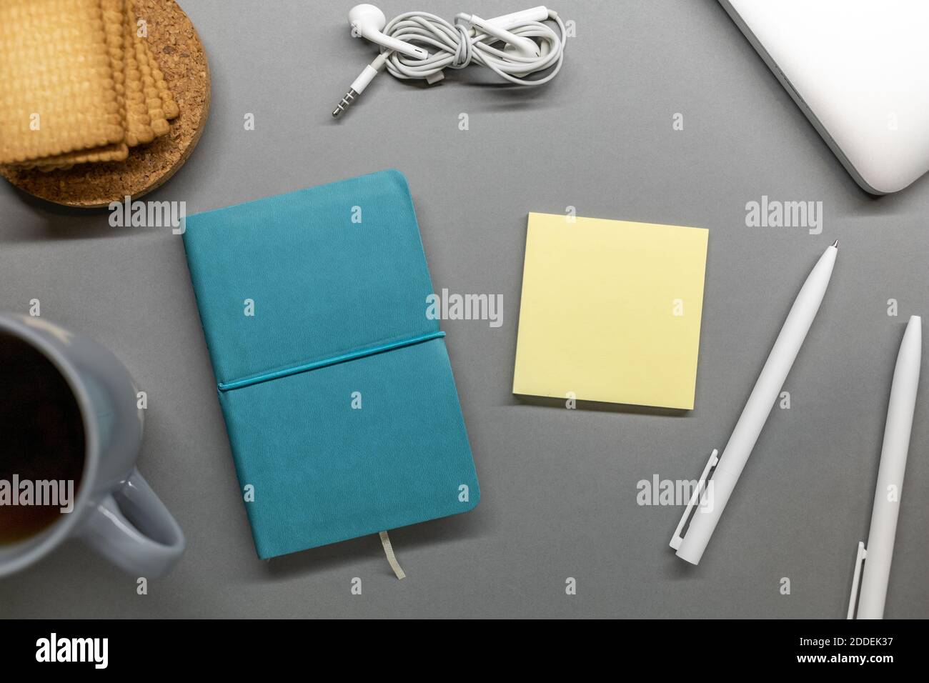 Blaue Notebook Tasse Cookie und Stifte auf grauem Tisch Stockfoto