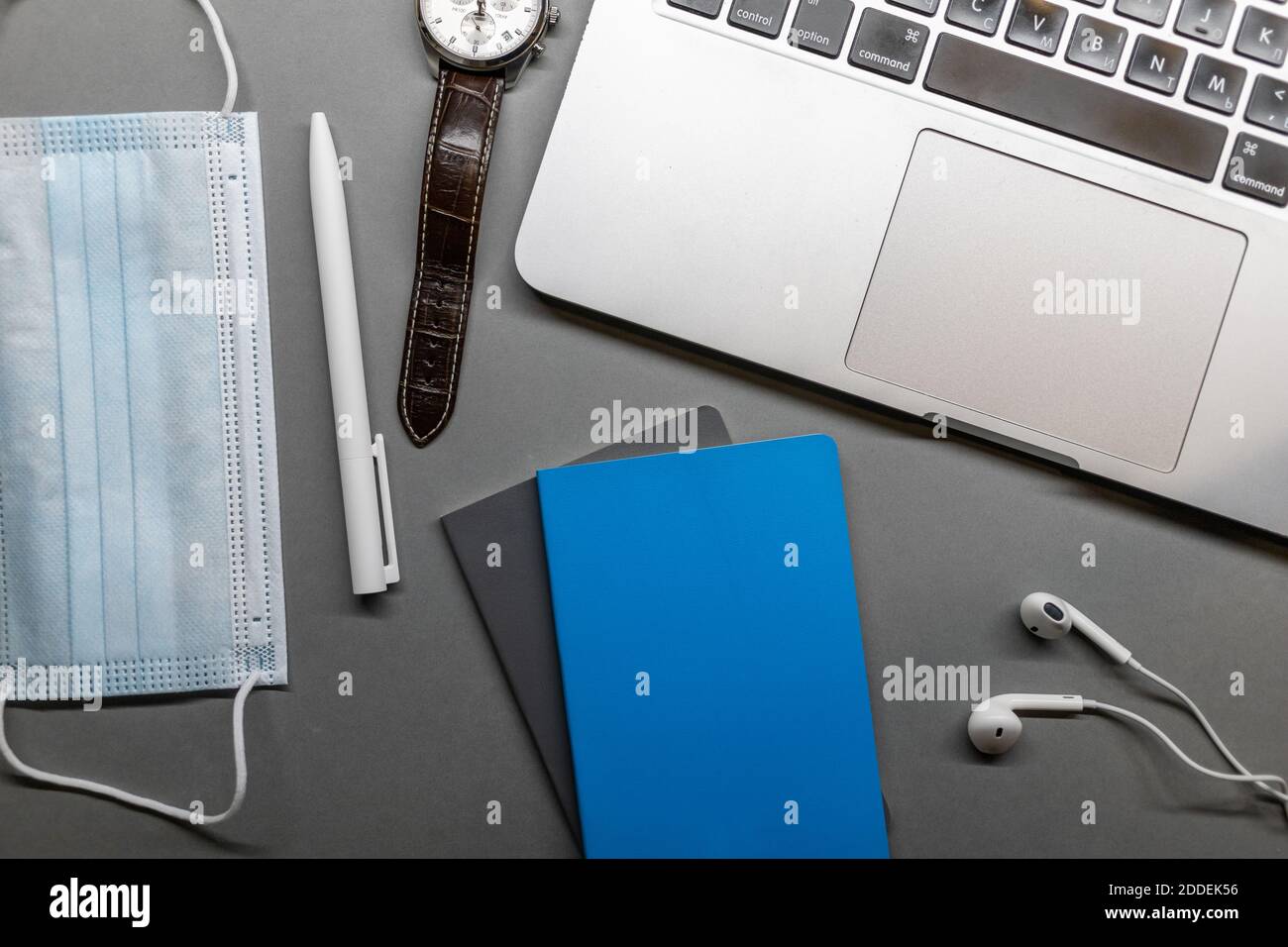 Notebook Laptop Gesichtsmaske Uhr und Stift auf grauem Tisch Stockfoto