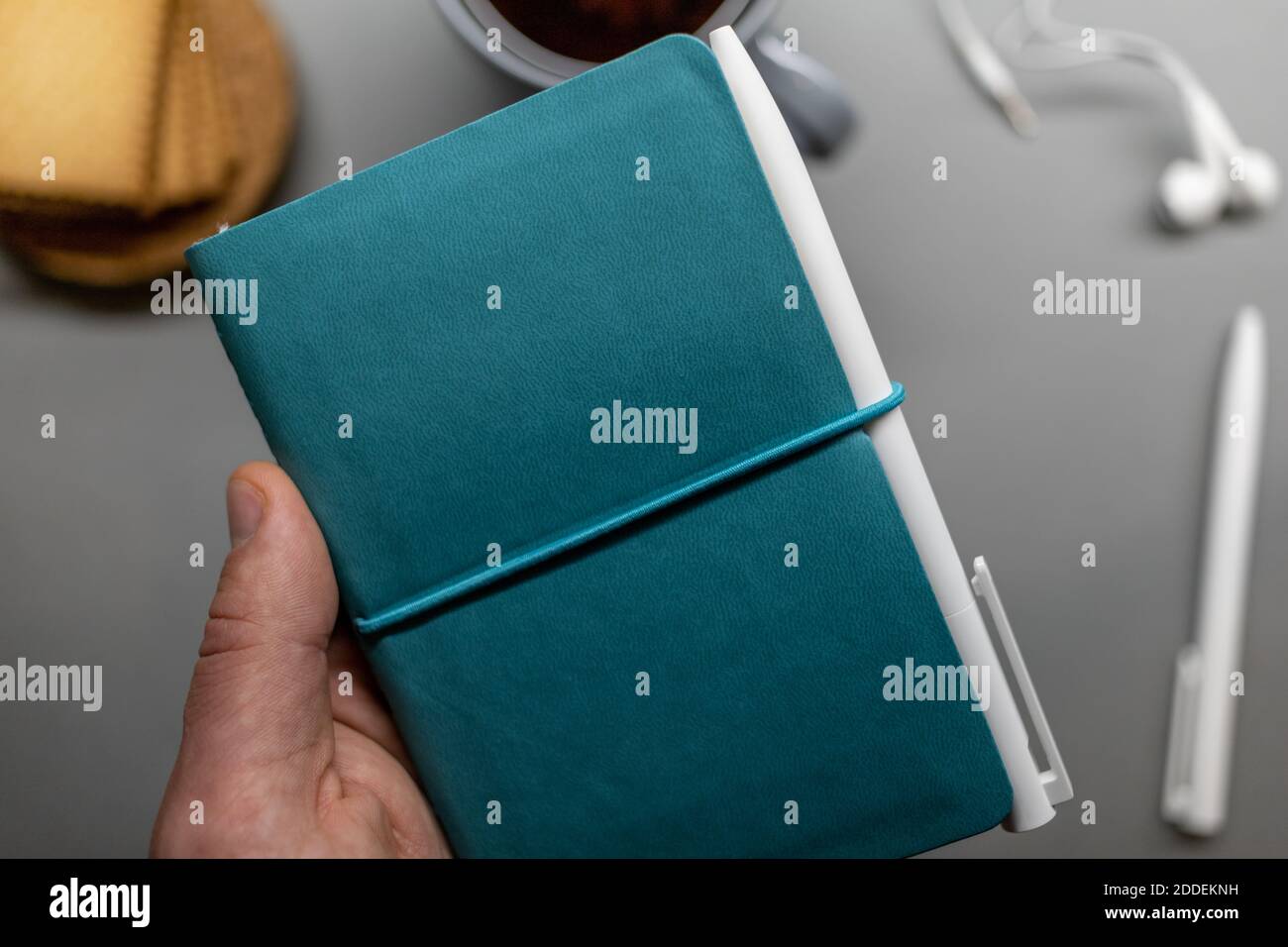 Blaues geschlossenes Notizbuch in Hand über Arbeitstisch Stockfoto