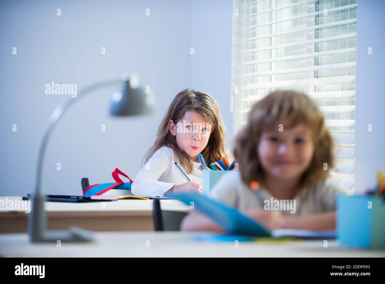 Schüler im Klassenzimmer in der Schule. Kleine Schüler beschäftigen sich mit dem Schreiben in ihren Copybooks. Stockfoto