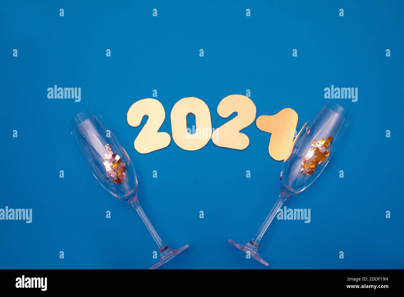 Goldene Zahlen 2021 auf blauem Hintergrund. Neujahr. Frohes neues Jahr 2021 mit Gläsern Champagner und Konfetti Stockfoto