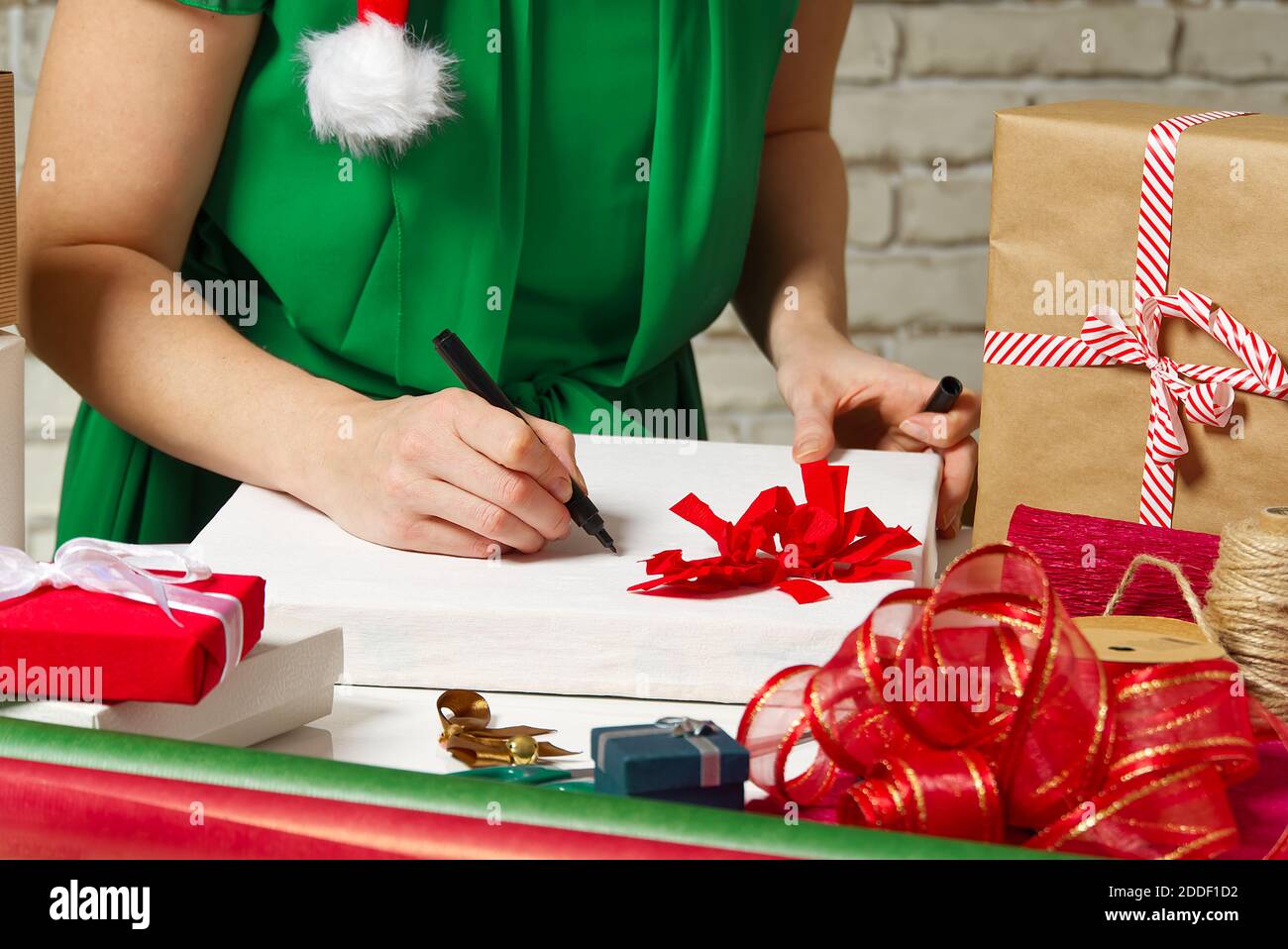 Frau unterzeichnet weihnachtsgeschenke mit einem schwarzen Stift. weihnachtsgeschenke Verpackung Stockfoto