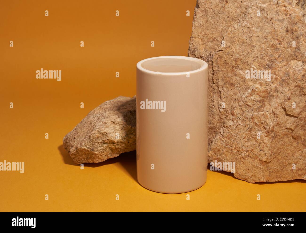 Beigefarbenes Keramik-Podium mit Steinen auf gelbem Hintergrund, natürliches Podium, Produktdisplay Stockfoto