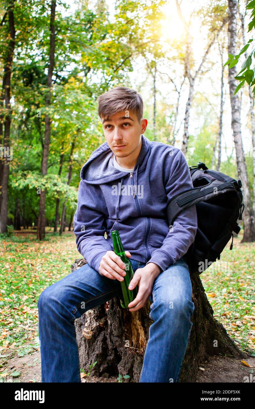 Junger Mann mit einer Flasche Bier im Wald Allein Stockfoto