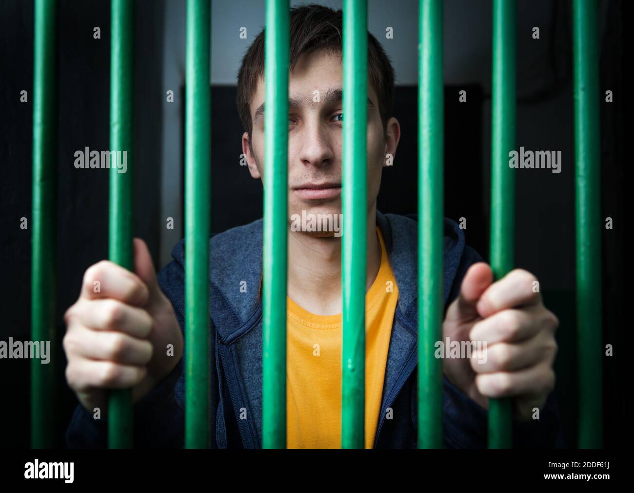 Eingesperrt junger Täter hinter Gittern in einer Zelle Stockfoto