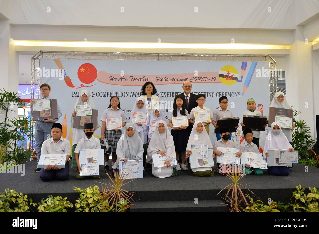 Bandar Seri Begawan, Brunei. November 2020. Chinesischer Botschafter in Brunei Yu Hong (L, Rückseite) und Bruneis Bildungsminister Haji Hamzah (R, Rückseite) posieren für ein Gruppenfoto mit Preisträgern eines Malwettbewerbs zum Thema "gemeinsam kämpfen wir gegen die COVID-19" in Bandar Seri Begawan, Hauptstadt von Brunei, 24. November 2020. Organisiert von der chinesischen Botschaft in Brunei und dem Bildungsministerium von Brunei, fand hier am Dienstag die Preisverleihung und die Ausstellungseröffnung eines Malwettbewerbs zum Thema "gemeinsam kämpfen wir gegen die COVID-19" statt. Quelle: Jeffrey Wong/Xinhua/Alamy Live News Stockfoto