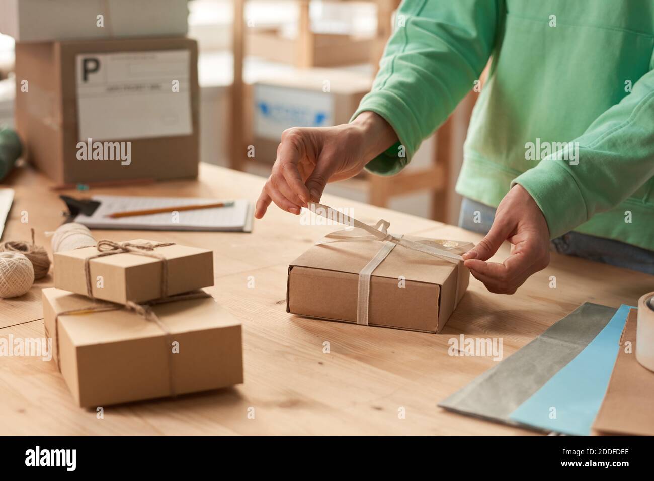 Nahaufnahme einer Frau, die am Tisch steht und ein Geschenk dekoriert Boxen mit Bändern zum Urlaub Stockfoto