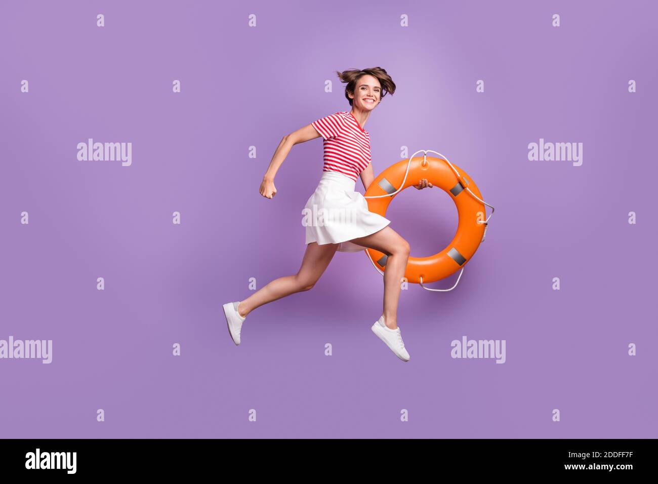 In voller Länge Profil Foto von Mädchen springen tun halten Gummi Ring tragen gestreifte T-Shirt Minirock Schuhe isoliert violett Farbe Hintergrund Stockfoto