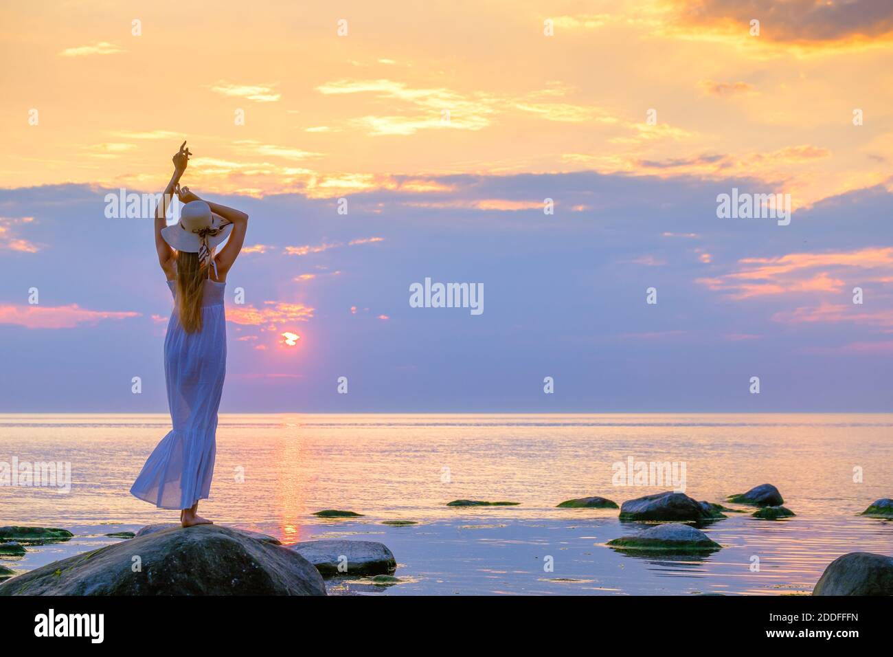 Schlanke Frau in Kleid genießen Sonnenuntergang über dem Meer Stockfoto