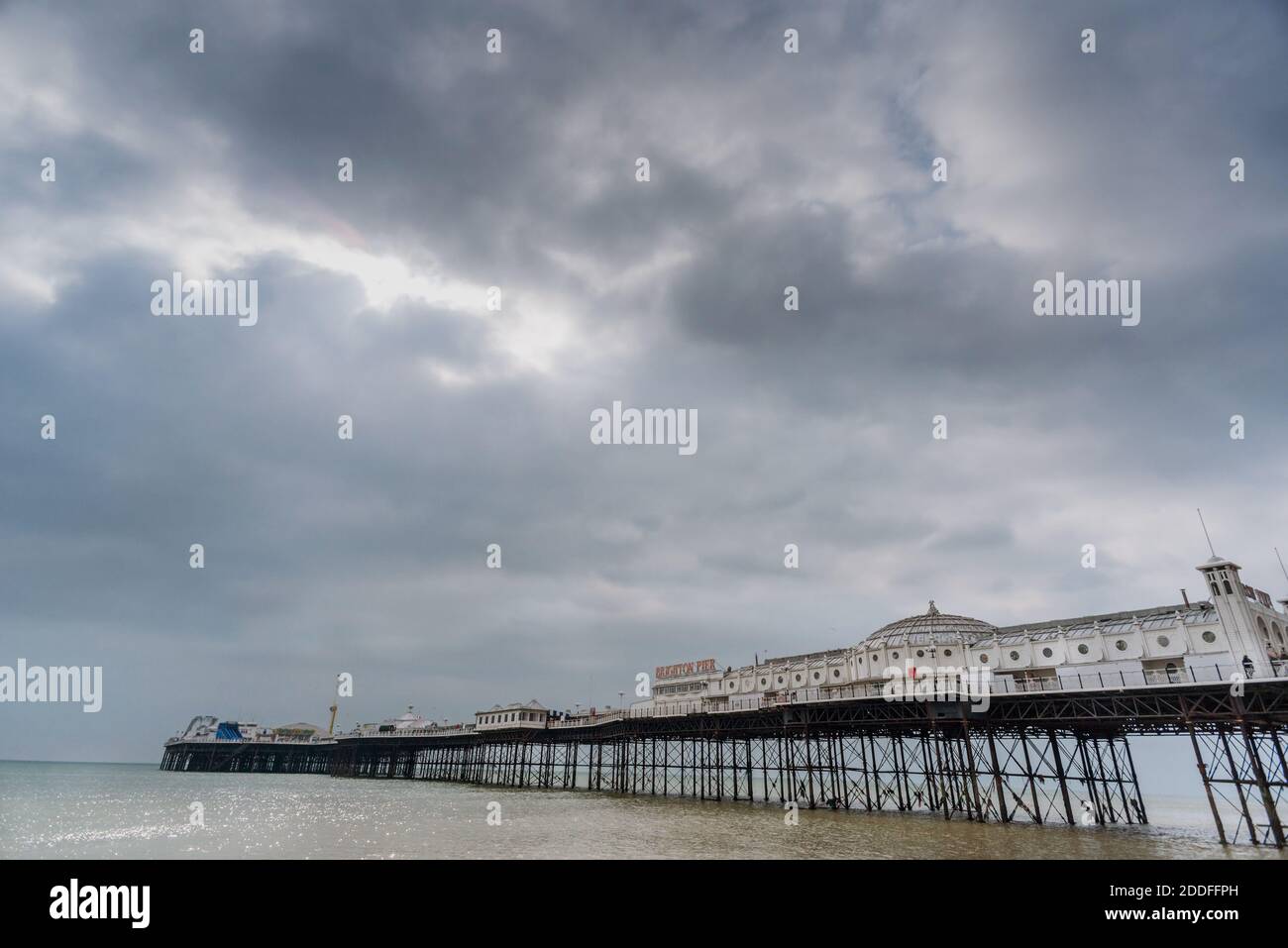 Der ikonische viktorianische Pleasure Pier, symbolisch für die Stadt, ragt in den englischen Kanal, während die Sonne versucht, durch den winterlichen Himmel darüber zu poken. Stockfoto