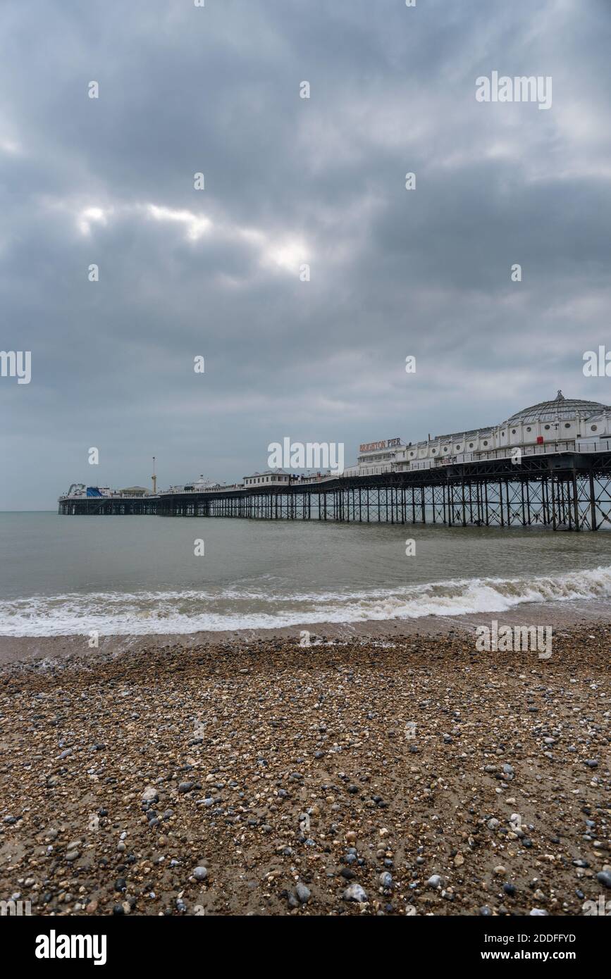 Der ikonische viktorianische Pleasure Pier, symbolisch für die Stadt, ragt in den englischen Kanal, während die Sonne versucht, durch den winterlichen Himmel darüber zu poken. Stockfoto