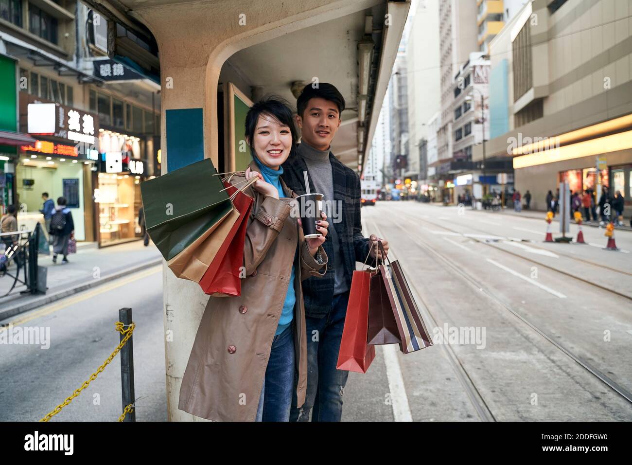 Glücklich junge asiatische Paar wartet auf Bus nach dem Einkaufen in Die Stadt Stockfoto