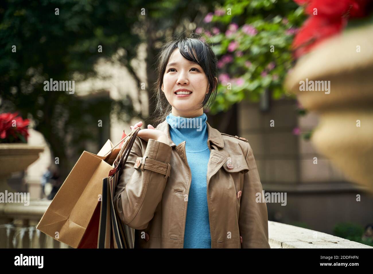 Junge asiatische modische Frau mit Einkaufstaschen, glücklich und lächelnd Stockfoto