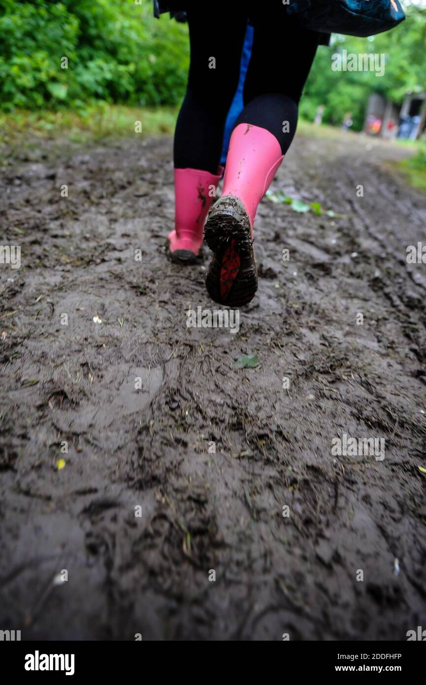 Geringe Schärfentiefe (selektiver Fokus) mit einer jungen Dame in rosa Gummistiefeln auf einer schlammigen unbefestigten Straße bei einem Musikfestival. Stockfoto