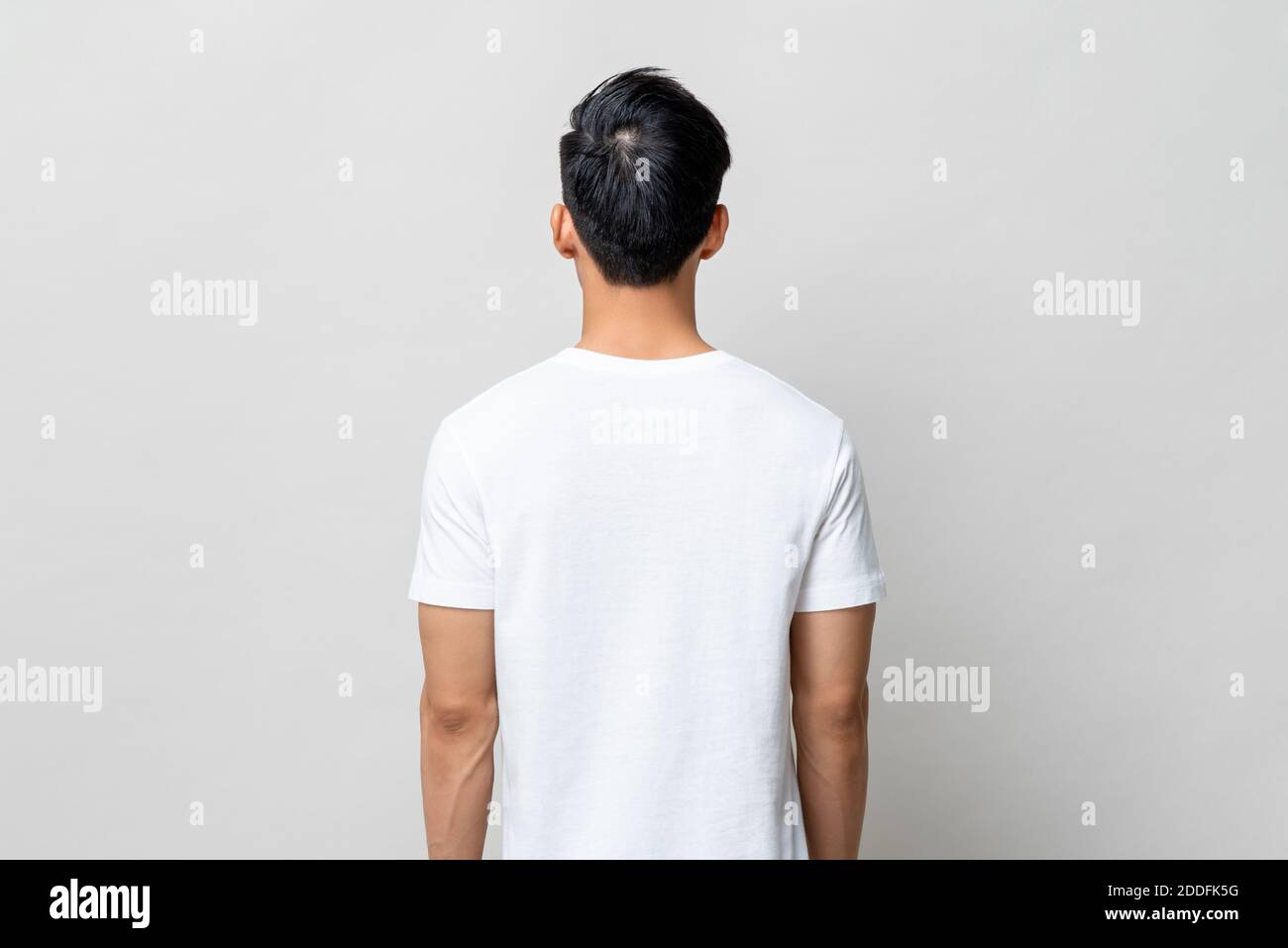 Rückansicht eines jungen Mannes mit einfarbigem weißen T-Shirt Hellgrauer isolierter Hintergrund Stockfoto