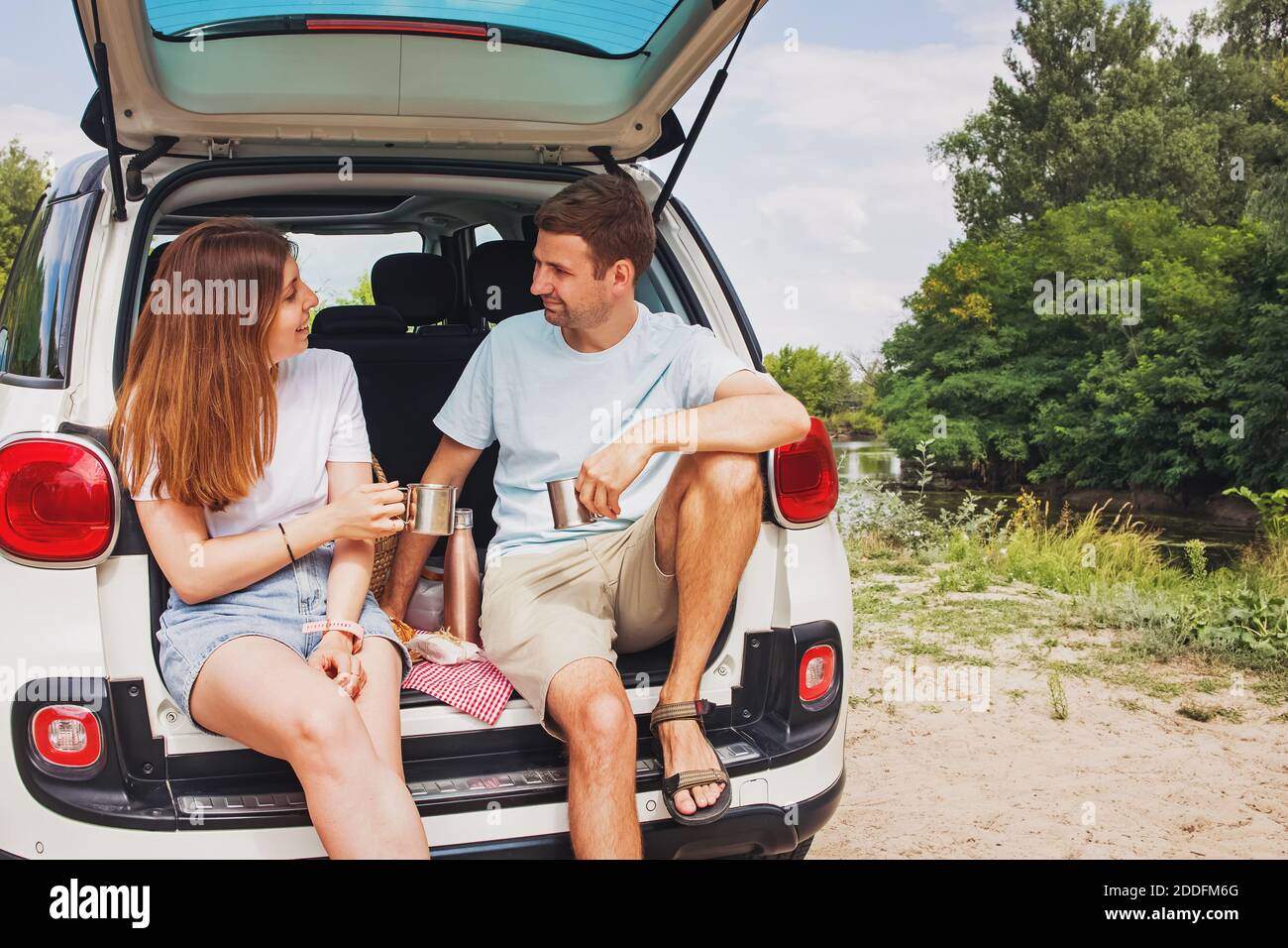 Mann und Frau sitzen in einem Kofferraum ihres Autos Picknick machen Stockfoto