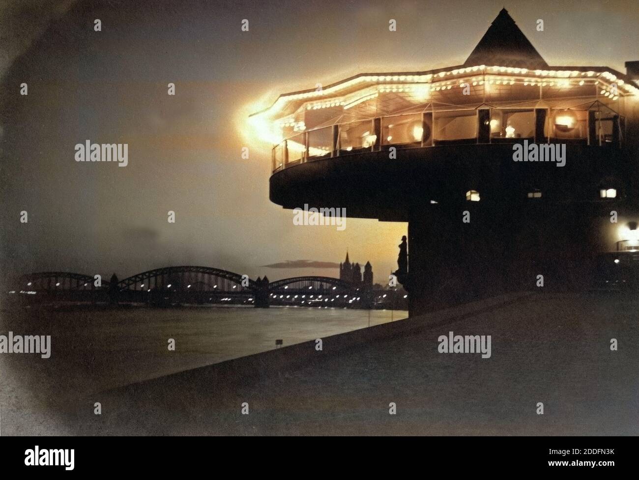 Blick Auf sterben Bastel, sterben Hohenzollernbrücke Und Die Altstadt Mit der Kirche Groß St. Martin bin Rheinufer Bei Nacht in Köln, Deutschland 1920er Jahre. Blick auf Restaurant Bastei, Hohenzollernbruecke Brücke, alte Stadt mit grober St.-Martins Kirche mit Rhein in Köln der 1920er Jahre. Stockfoto