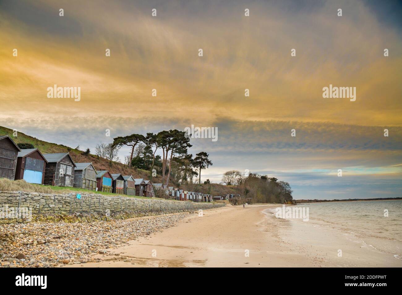 Strandhütten im Winter auf leerem britischen Strand im Winter mit dramatischem Sonnenuntergang Himmel. Stockfoto