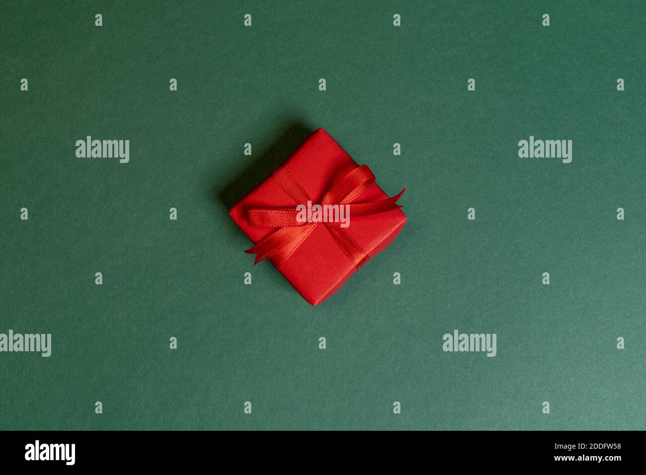 Ein rotes Weihnachtsgeschenk auf grünem Hintergrund Stockfoto
