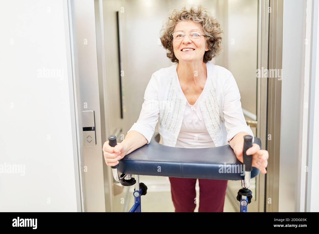 Glückliche ältere Frau mit Rollator im Aufzug aus dem Pflegeheim Stockfoto