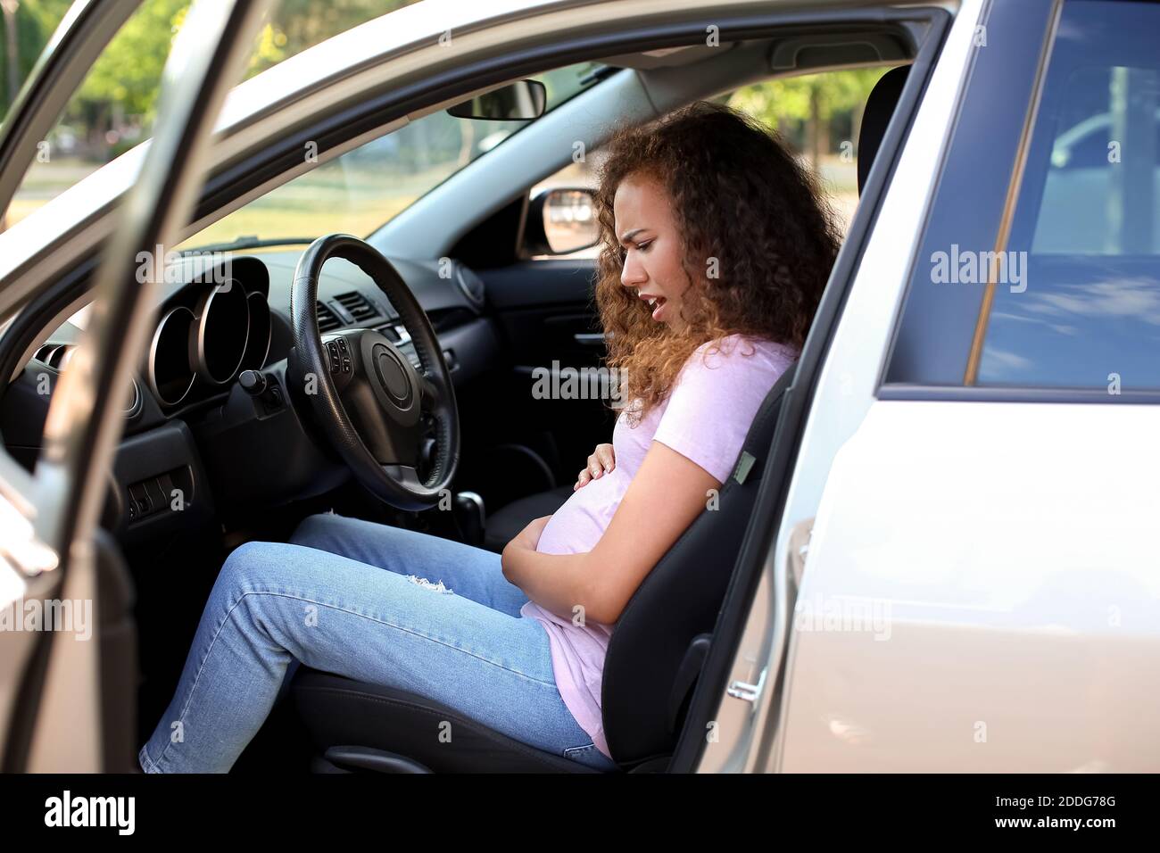 Schwangere afroamerikanische Frau Gefühl Geburt Kontraktionen im Auto Stockfoto