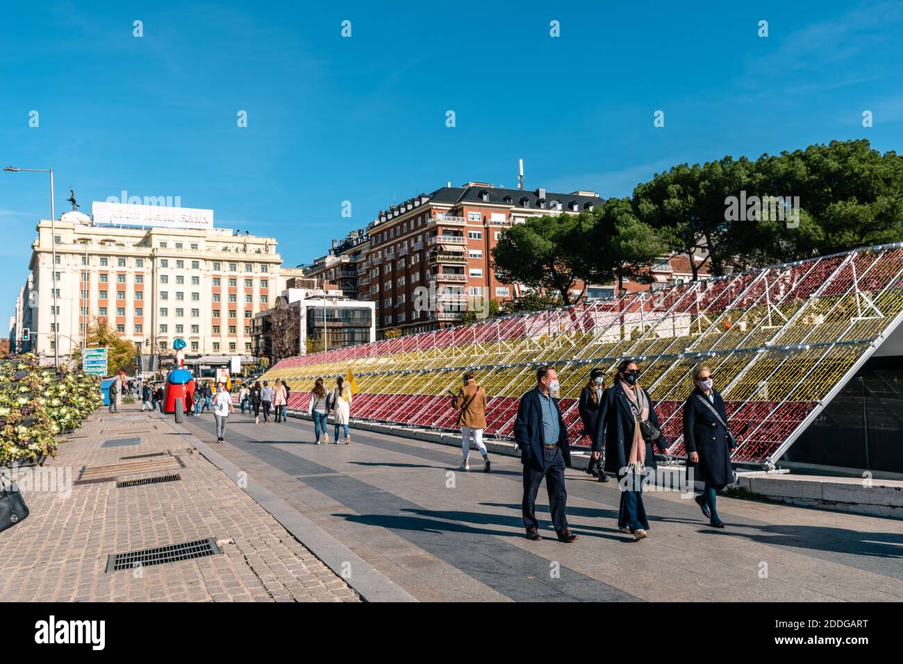 Madrid, Spanien - 22. November 2020: Weihnachtsdekoration mit spanischer Flagge auf der Plaza de Colon. Menschen gehen einen sonnigen Tag Stockfoto