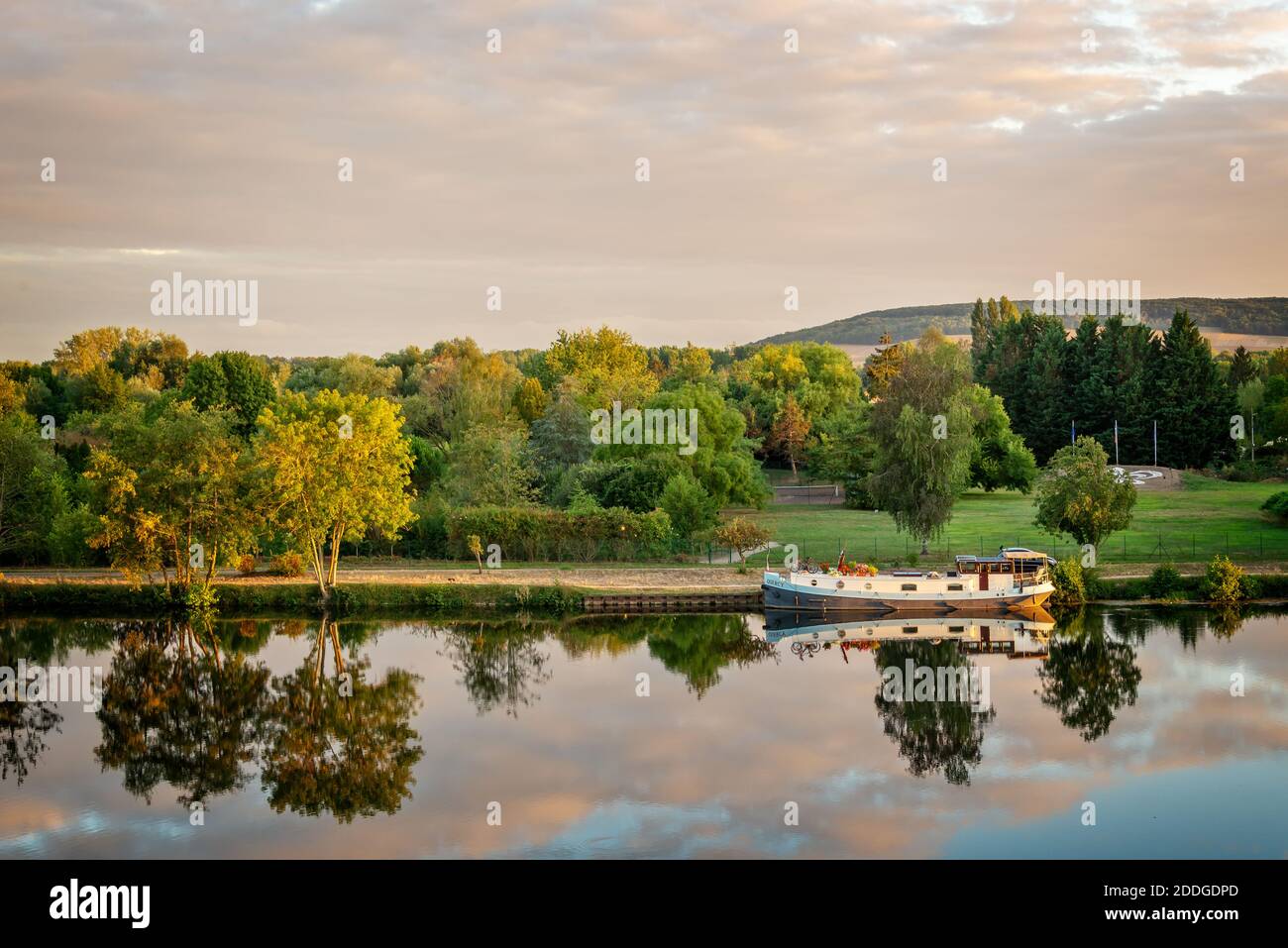 Boot auf dem Fluss Yonne mit Reflexionen bei Sonnenuntergang bei Joigny in Burgund, Frankreich. Stockfoto