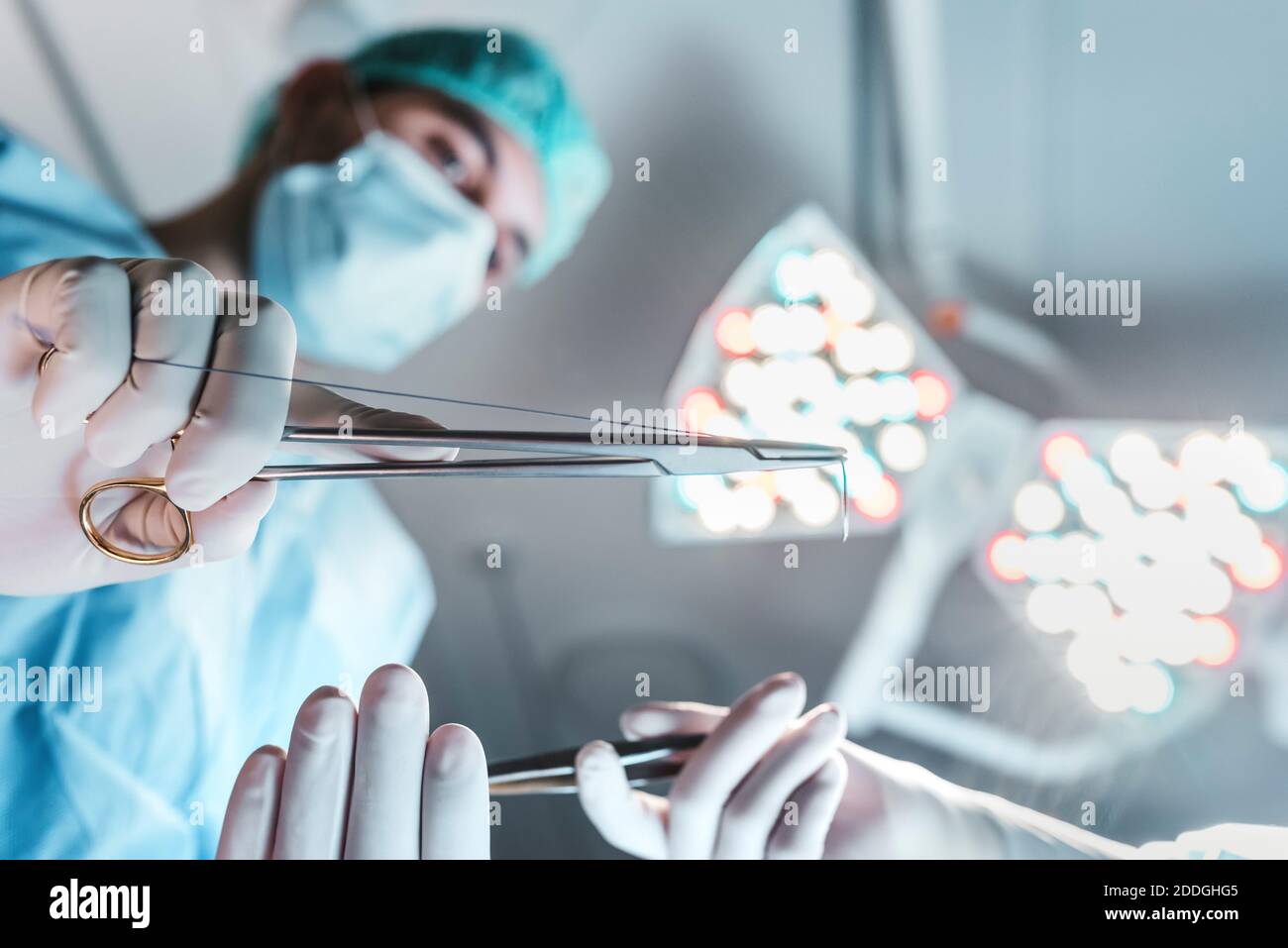 Von der unteren Seite Ansicht des fokussierten professionellen Chirurgen mit medizinischen Scheren arbeiten im Operationssaal in modernen Krankenhaus Stockfoto