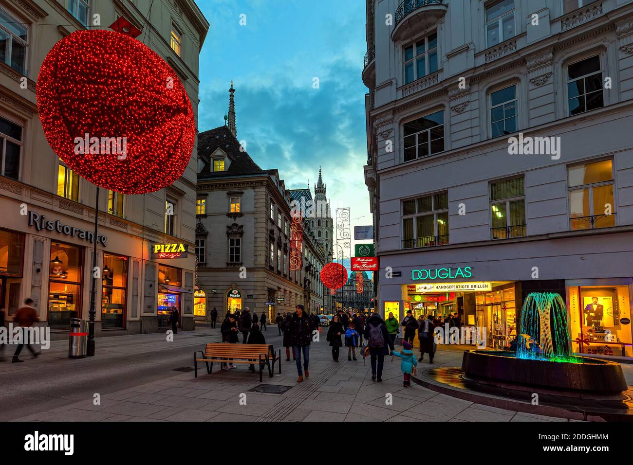 Menschen, die auf beleuchteten und dekorierten Abendstraßen im Zentrum von Wien - Hauptstadt von Österreich zu Fuß gehen. Stockfoto