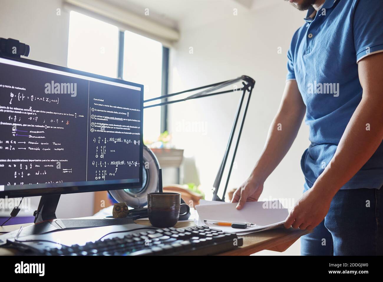 Crop unkenntlich männlichen Physik Student am Tisch mit Dokumenten stehen Und Computer zeigt verschiedene Formeln Stockfoto