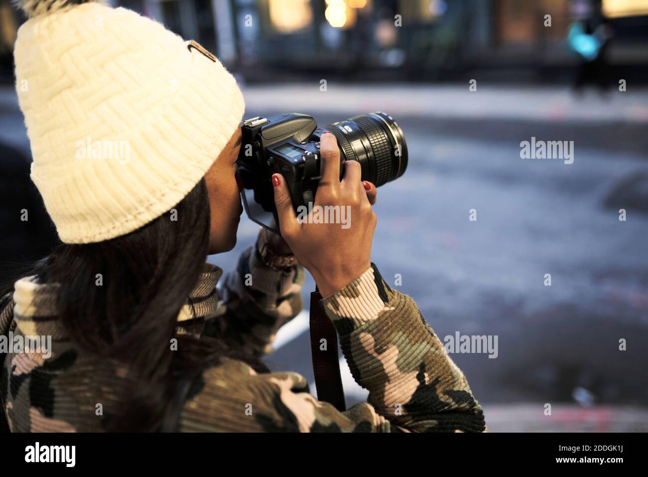 Seitenansicht einer afroamerikanischen Fotografin in warmem Hut Und stylischer Pullover, der moderne Fotokameras fotografiert New York City Stockfoto