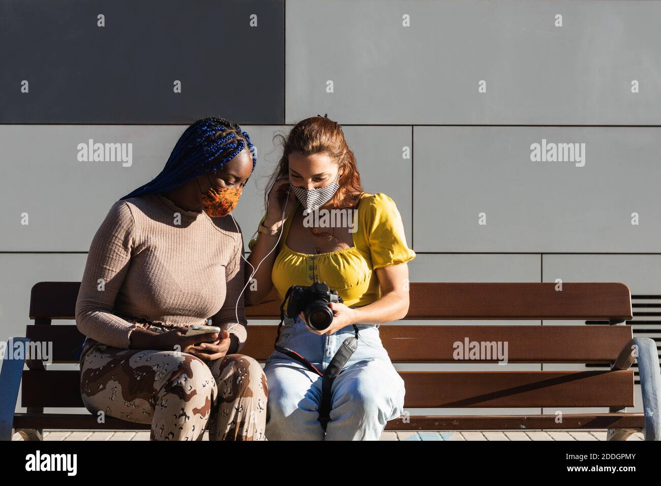 Begeisterte diverse Freundinnen, die Musik hören und durchschauen Fotos auf Fotokamera auf der Straße gemacht Stockfoto