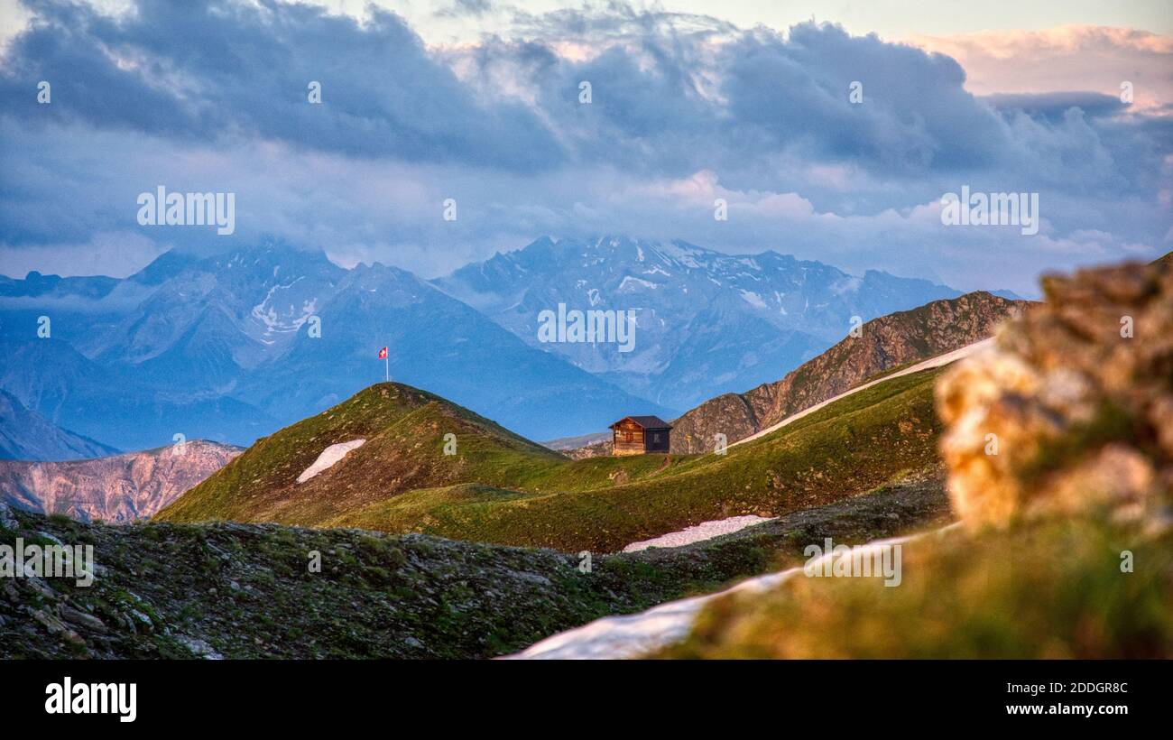 schweizer Berglandschaft mit Blick auf die schweizer Flagge auf dem Gipfel mit einer Almhütte, Chörbsch Horn, Chörbschhornhütte oberhalb Davos Graubünden Stockfoto