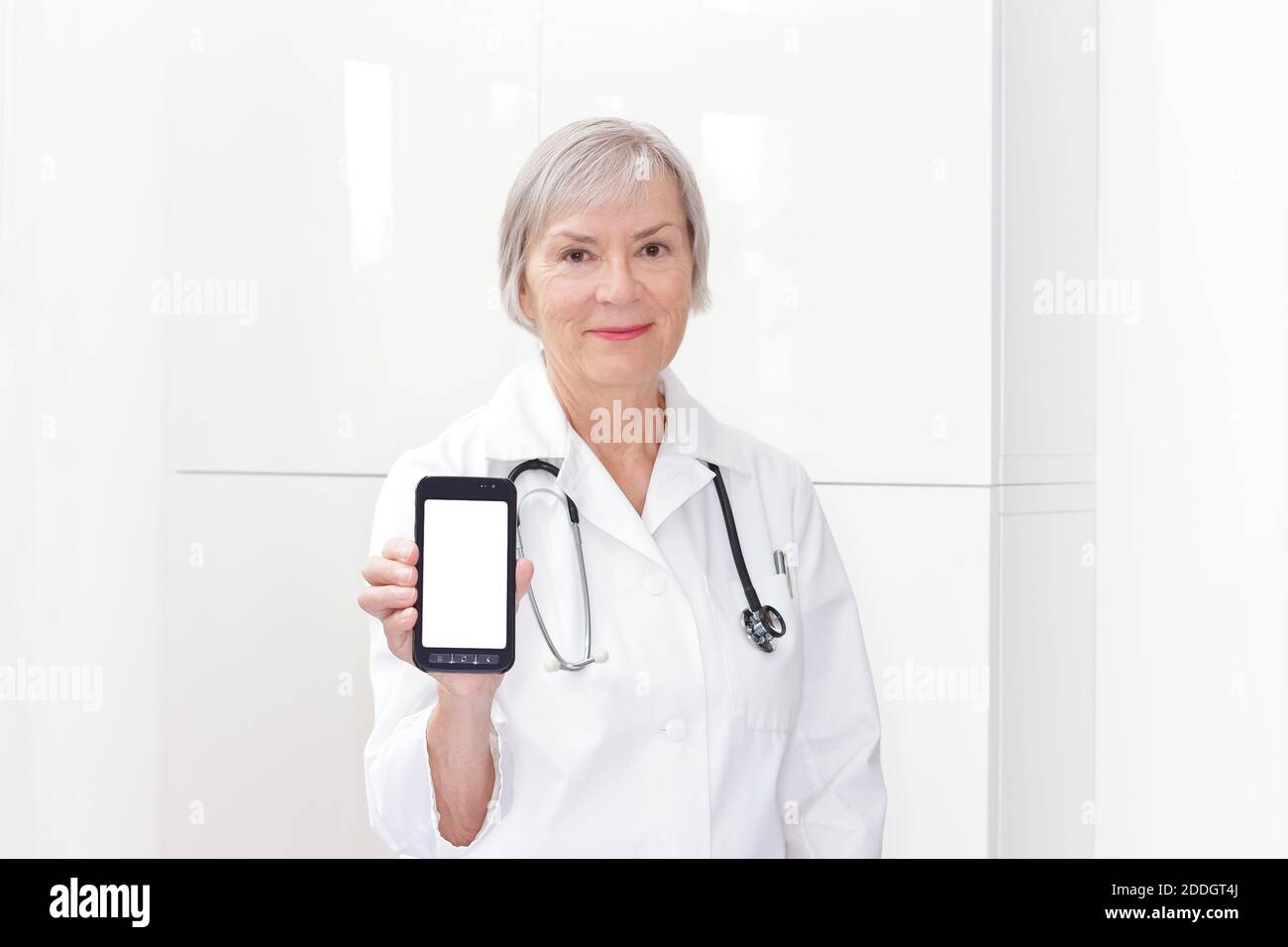 Freundliche Oberarzt hält ein Smartphone, Handy oder Handy, weißen Copyspace. E-Health-Vorlage. Stockfoto