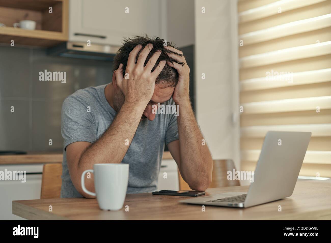 Enttäuschter Freiberufler im Heimbüro mit Jobproblemen mit dem Kopf in den Händen, selektiver Fokus Stockfoto