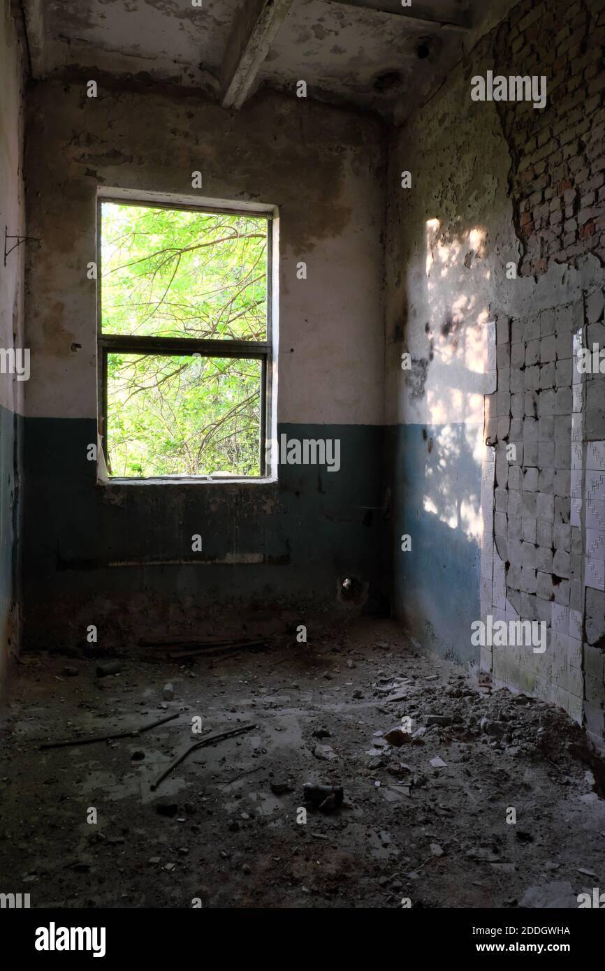 Die Fensterbeleuchtung beleuchtet einen verlassenen Raum. Verlassene Backsteingebäude. Stockfoto