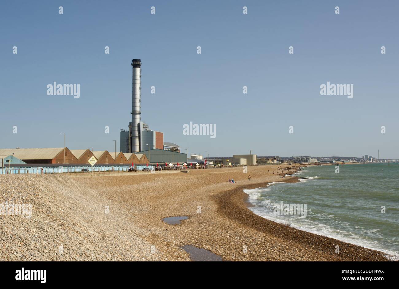 Strandpromenade in Shoreham, West Sussex, England. Mit Strandhütten, Cafe Hafengebäude und Kraftwerk Kamin. Stockfoto