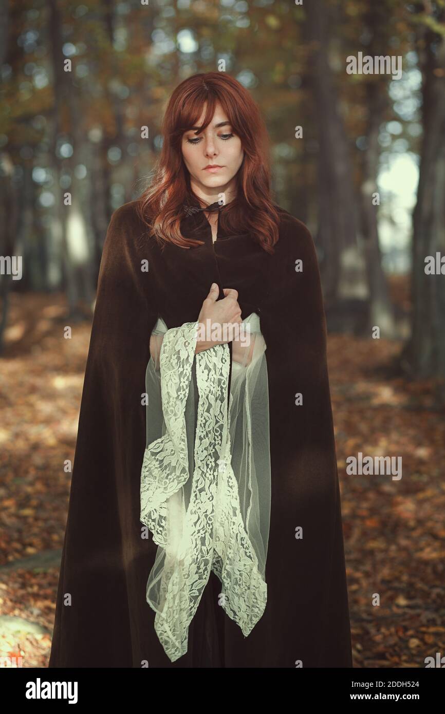 Schöne Frau allein im Wald. Mittelalterliches Kleid und Umhang Stockfoto